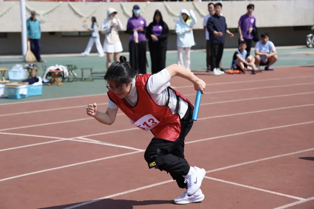 胡亚楠老师在运动场上手持接力棒奔跑